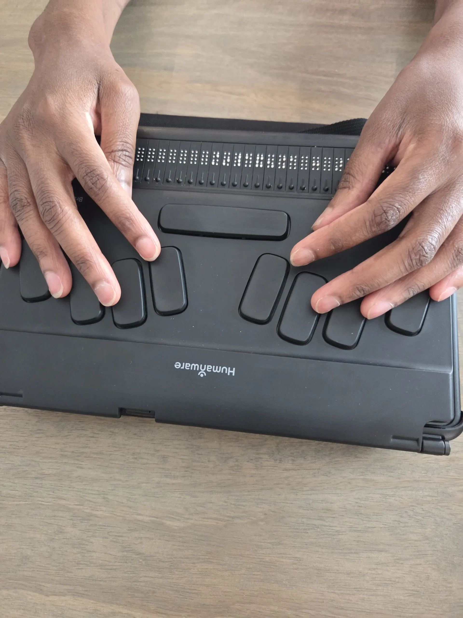 Hands using a Braille-enabled notetaker device